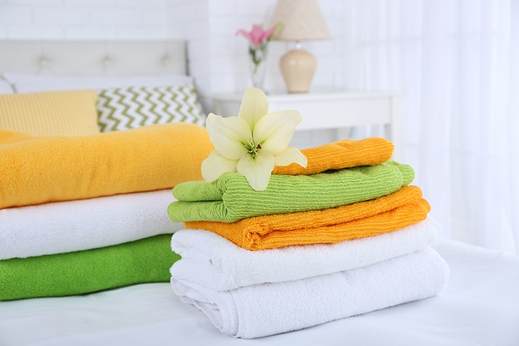 A flower and fluffy towels in a guest bedroom | Innovate Home Org | Columbus OH | #FreshTowels #GuestBedroom #ColumbusGuestBedroom