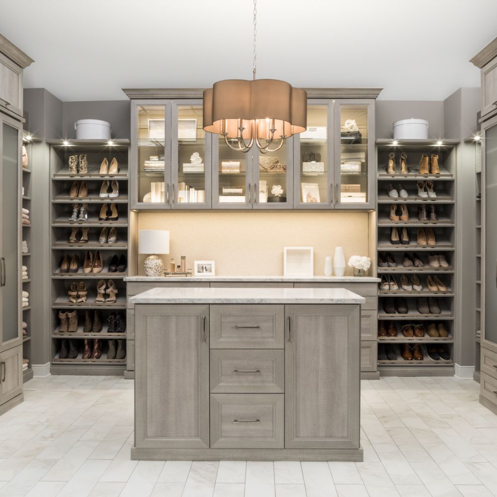 Luxury walk-in closet with center island, glass cabinets, and built-in shoe shelving in Columbus Ohio